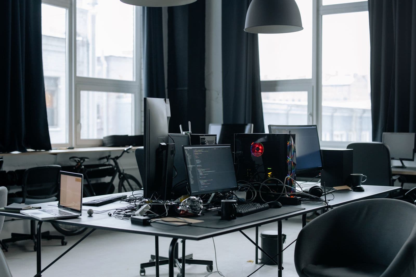 Desk with several screens, one showing program code, a laptop in front