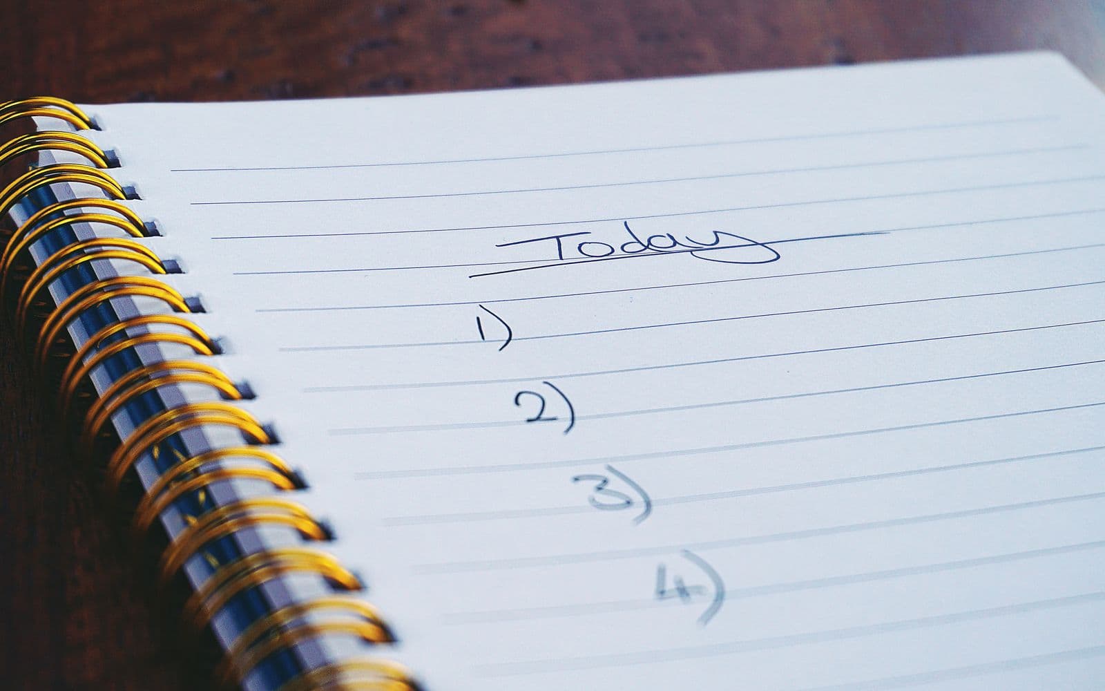 Spiral notepad on a dark wooden table with the handwritten heading Today and a numbered list below it