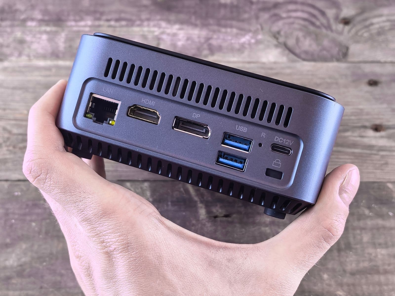 Kompakter Mini-PC mit Anschlüssen für LAN, HDMI, DisplayPort und USB wird in einer Hand gehalten