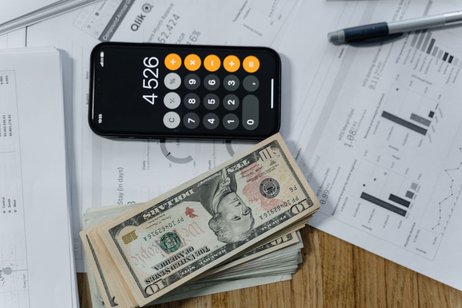 Smartphone calculator, banknotes, and financial statements on a desk