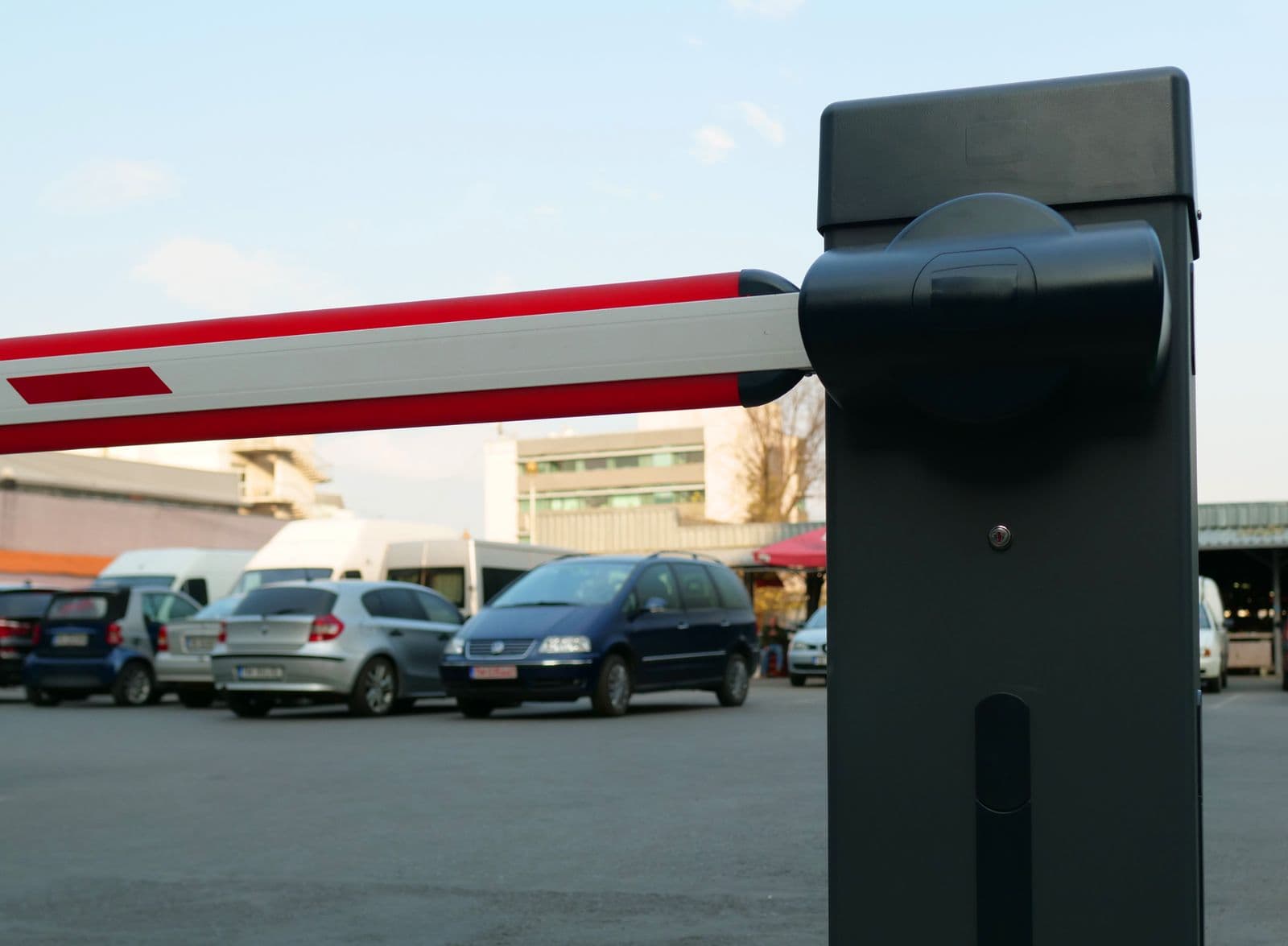 Automatische Schranke an einer Zufahrtskontrolle, im Hintergrund parkende Fahrzeuge