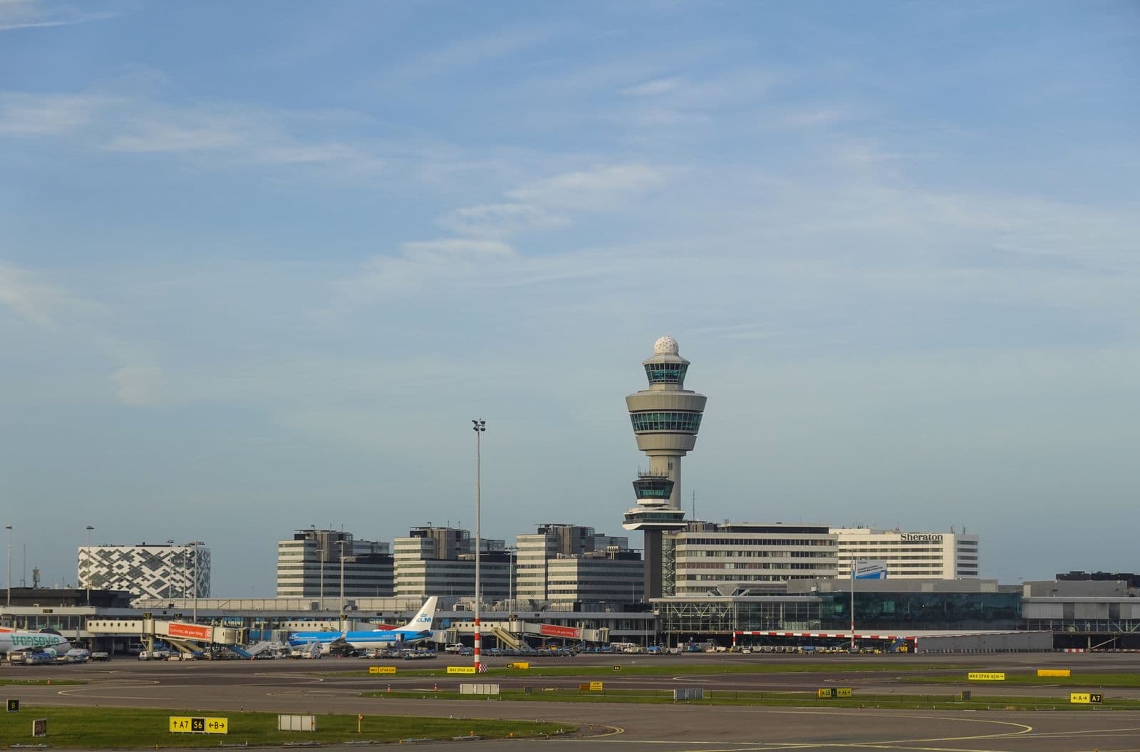 Kontrollturm eines Flughafens mit Blick auf das Vorfeld, auf dem mehrere Flugzeuge am Gate stehen