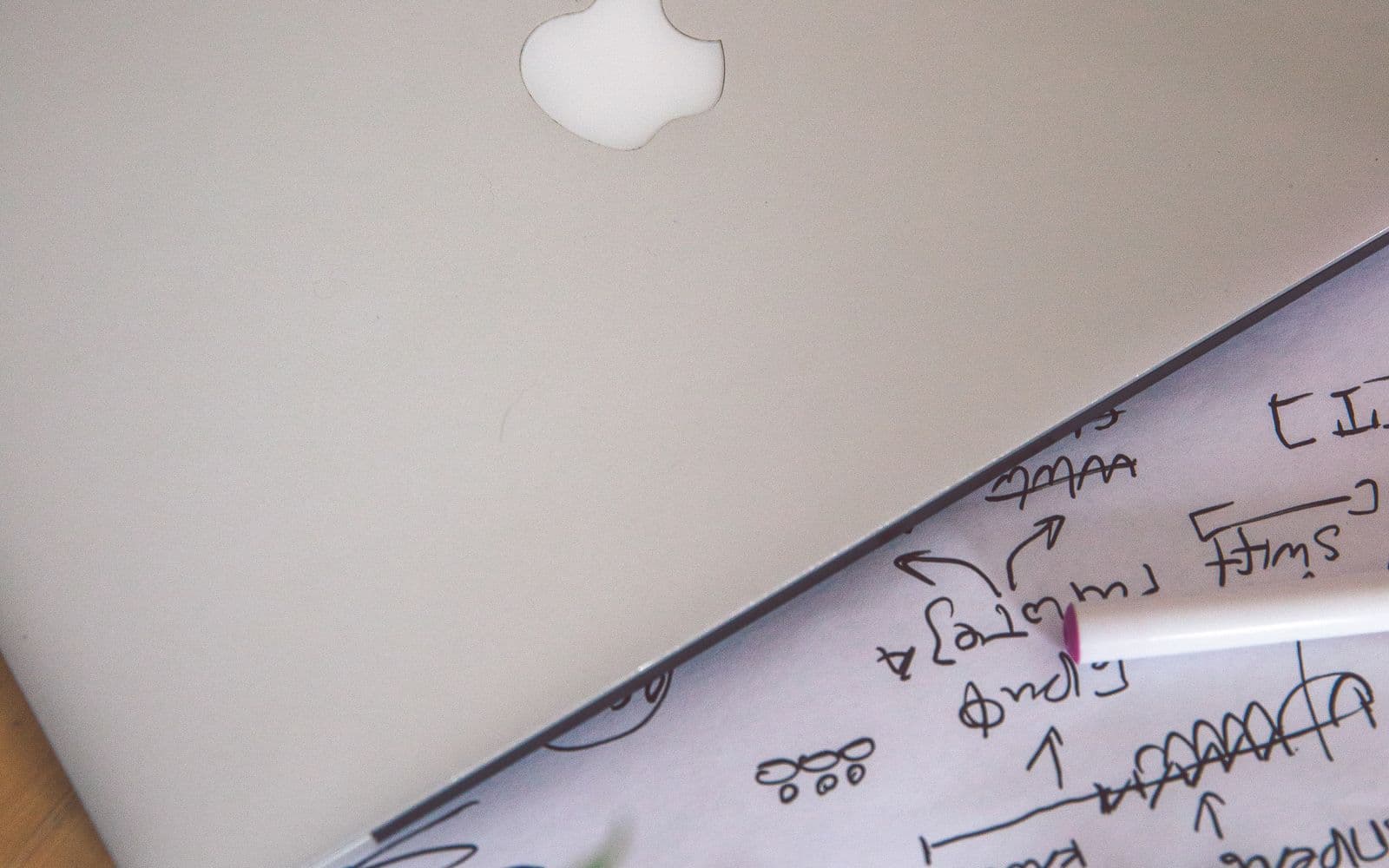 Aufgeklappter Laptop über einem Blatt mit handschriftlichen Notizen
