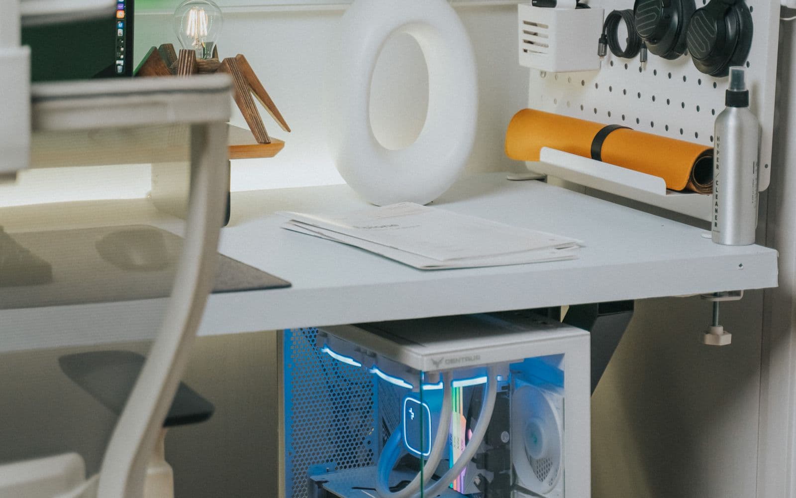 Bright workspace with a wall shelf and a blue-lit computer standing under the desk