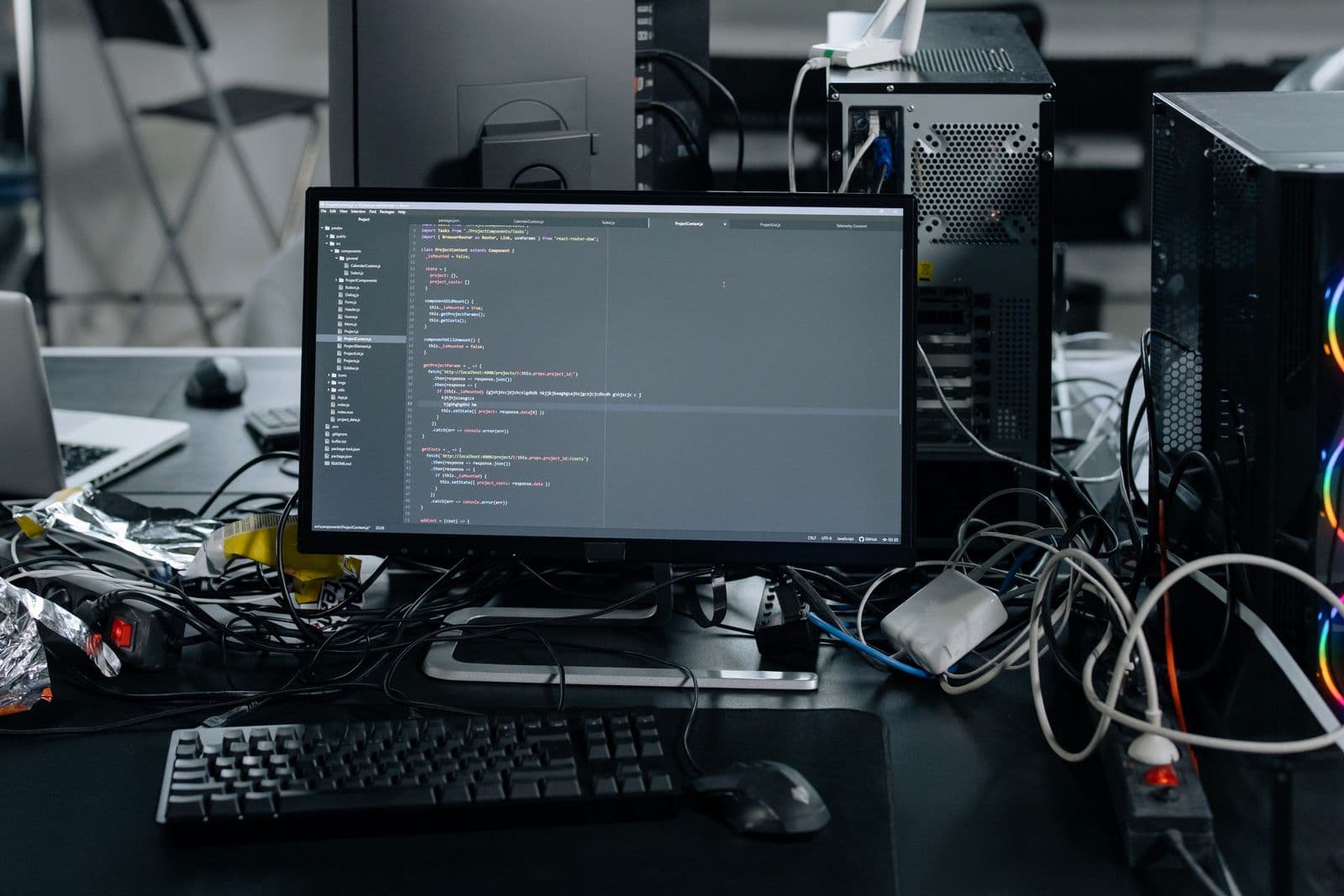 Monitor showing open program code in front of computer tower cases on an office desk