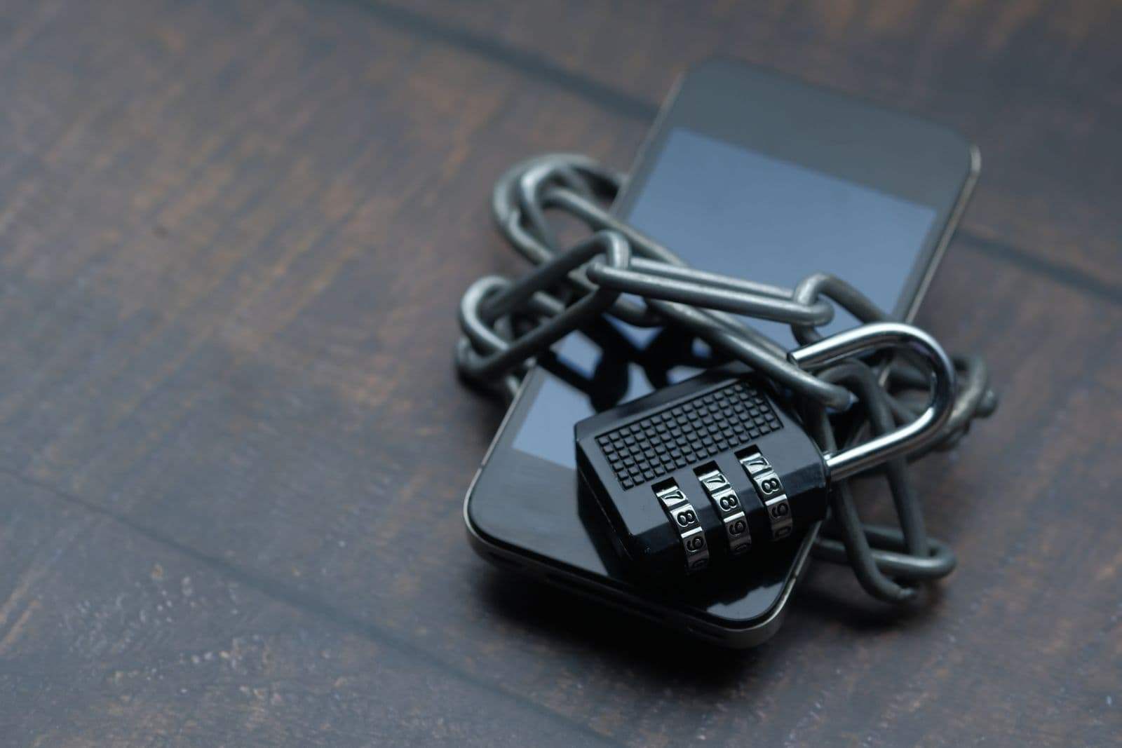 Smartphone with a chain and combination lock on a wooden table