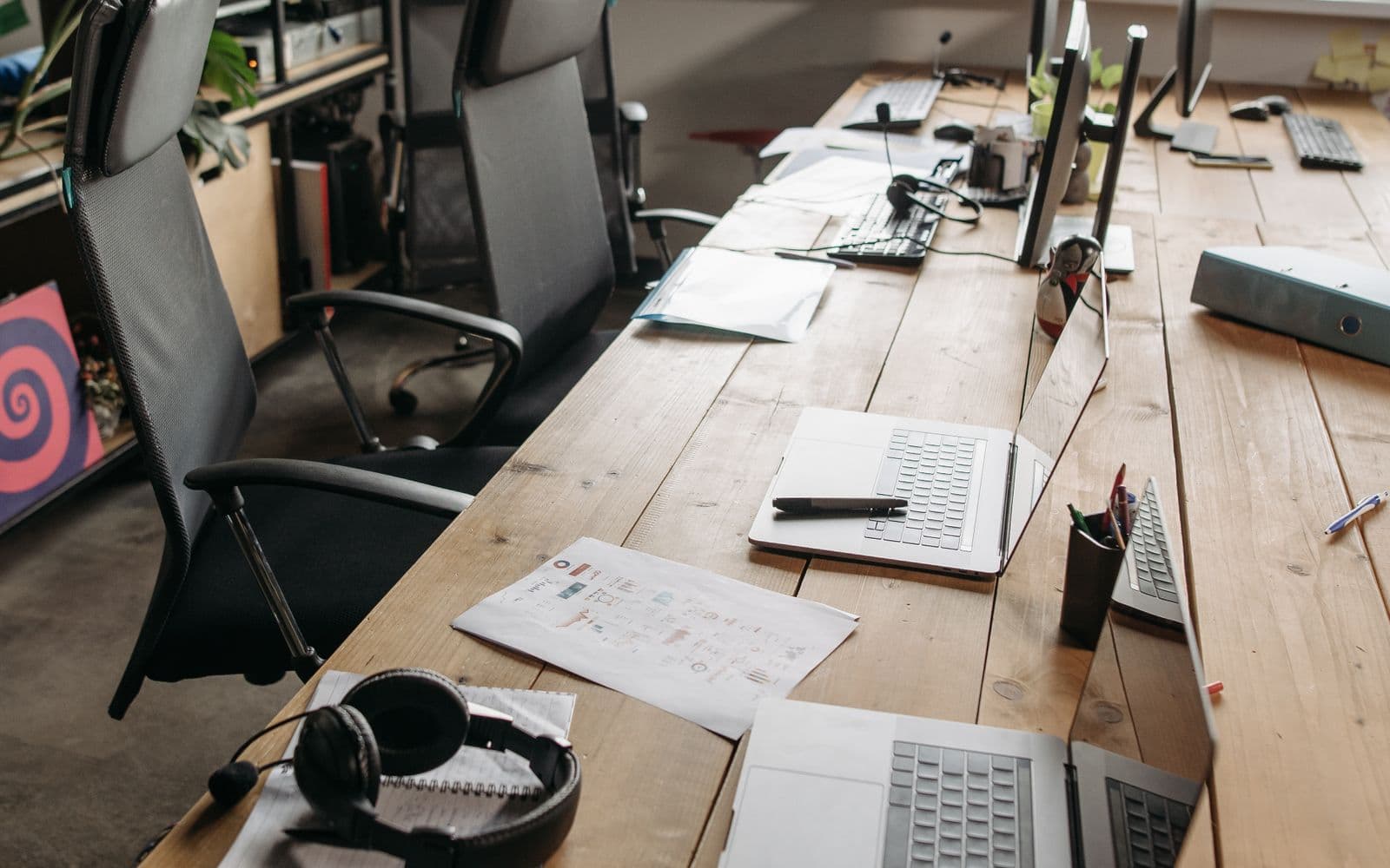 Arbeitsplätze mit Laptops und Headsets an einem großen Holztisch